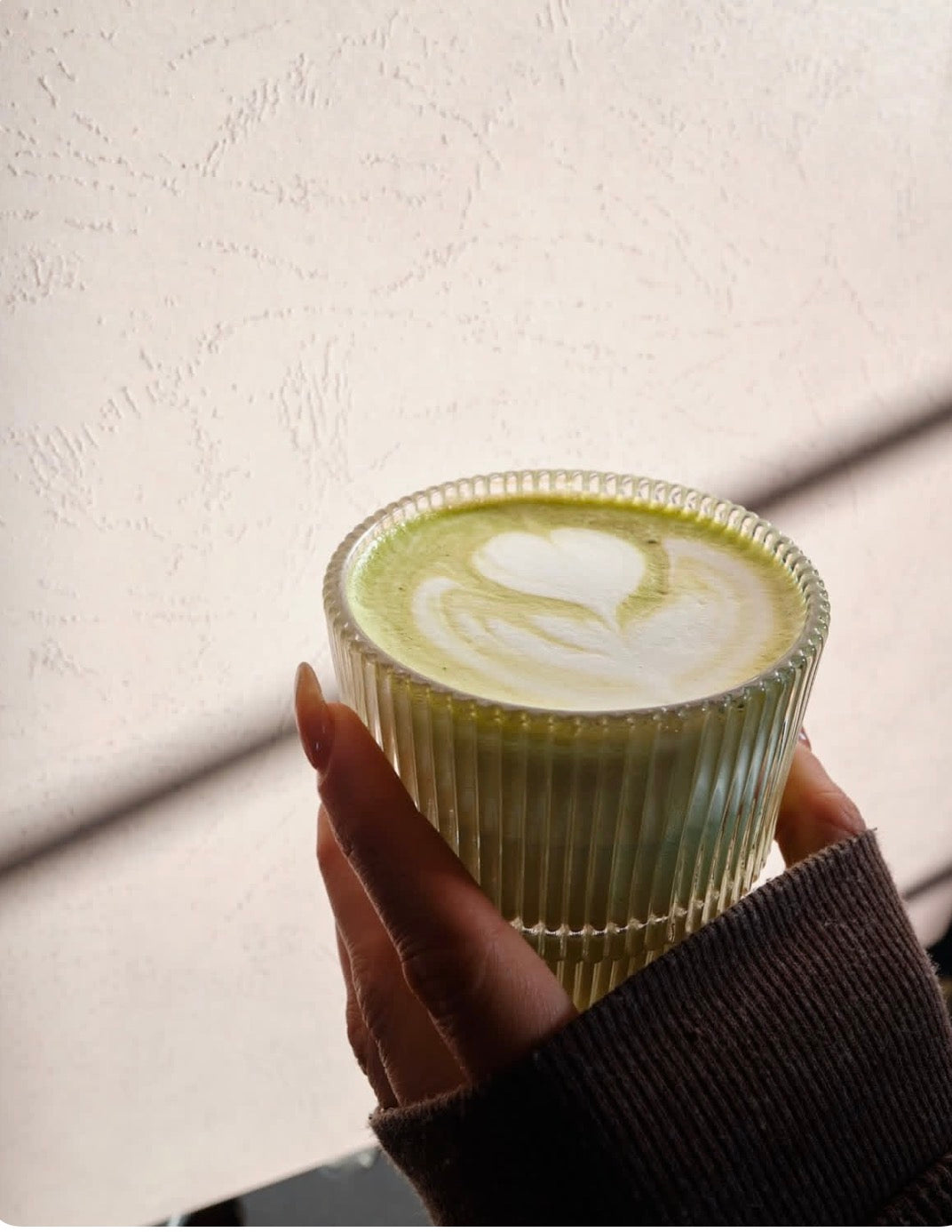 Ceremonial grade matcha latte with heart latte art in a ribbed glass