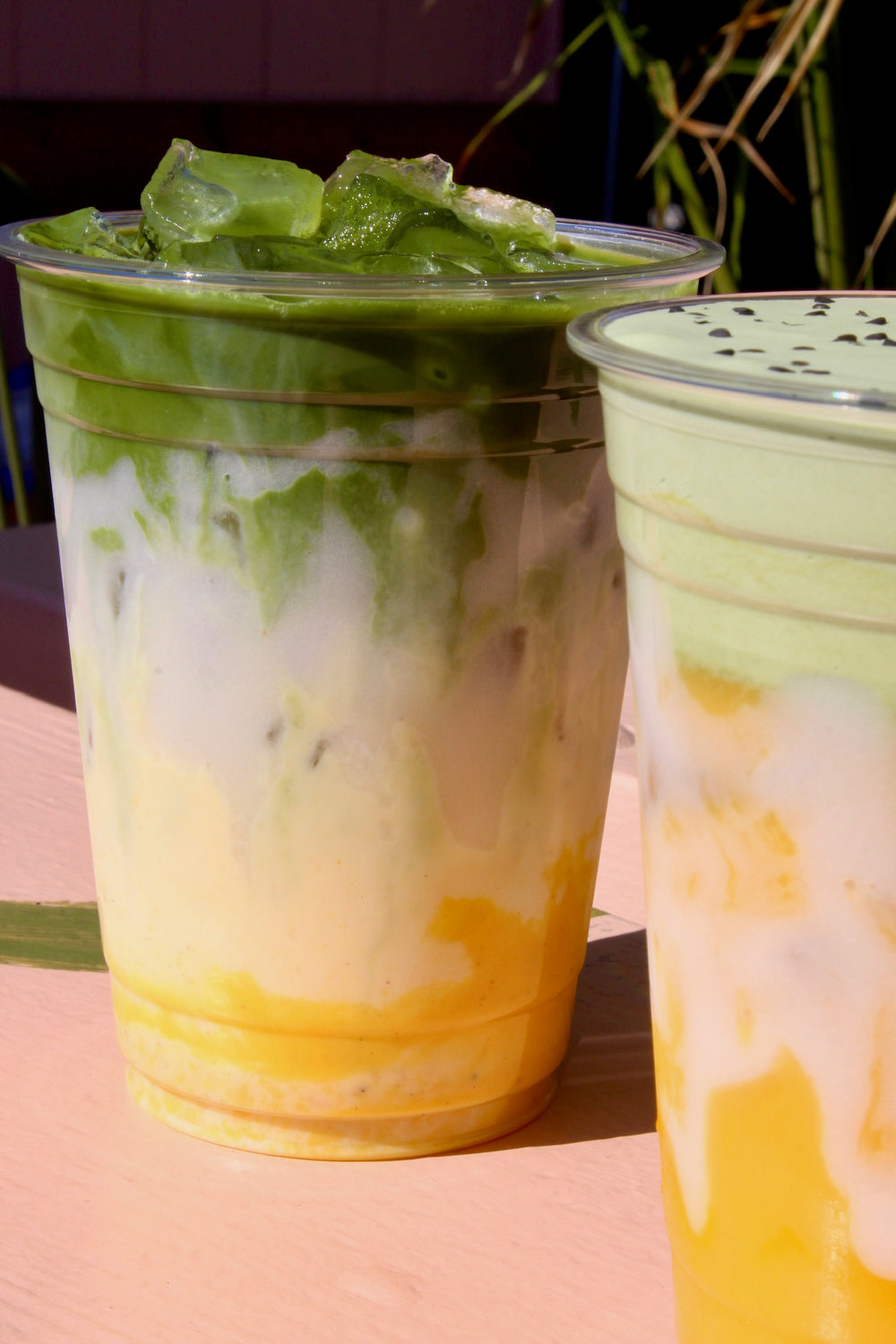 Layered iced matcha drinks with mango and cream