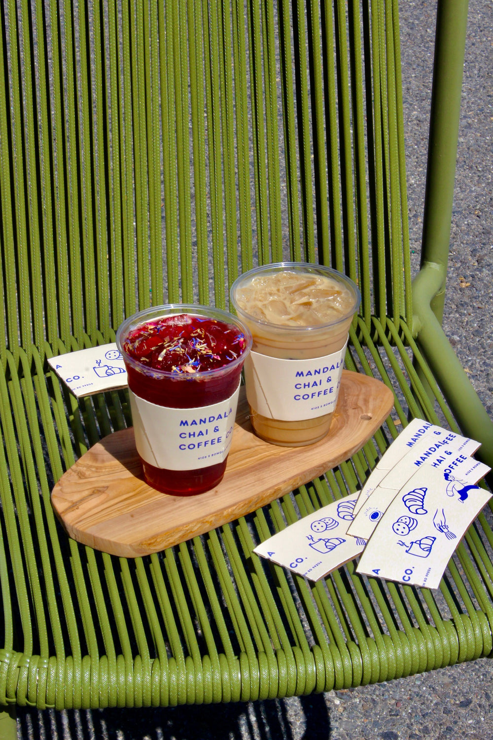 Hibiscus tea and iced latte on a wooden board with cup sleeves