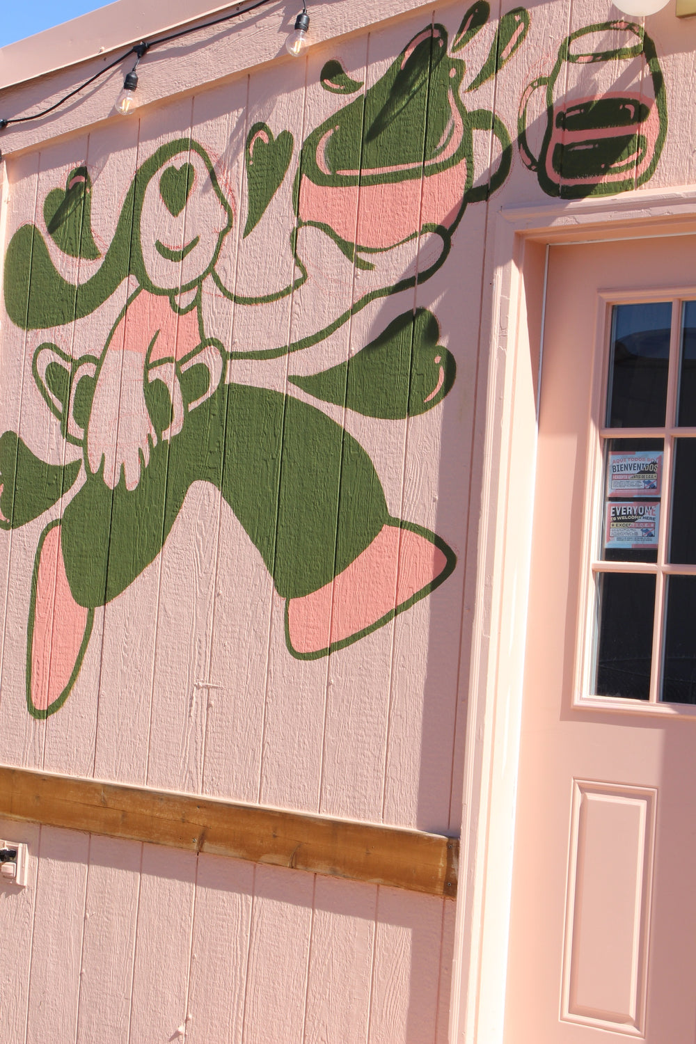 Pink and green mural of a character carrying a cup of coffee on the Mandala stand