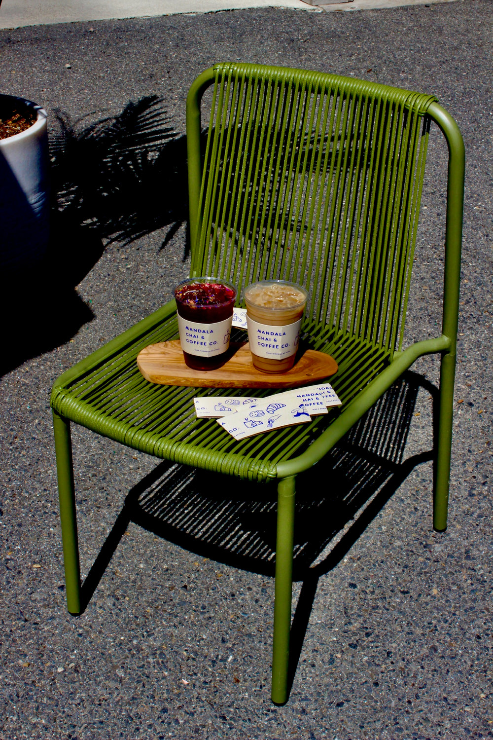Iced hibiscus tea and iced latte in Mandala cup sleeves on a green chair