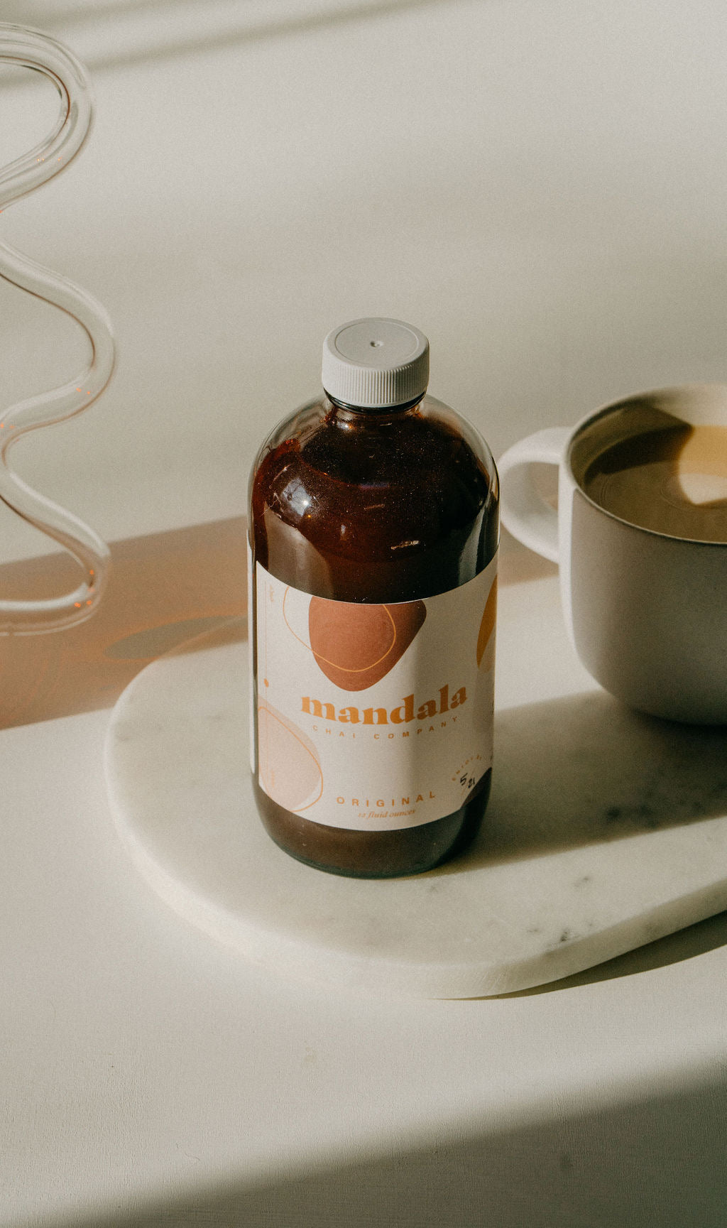 Original chai bottle in morning light with a latte mug