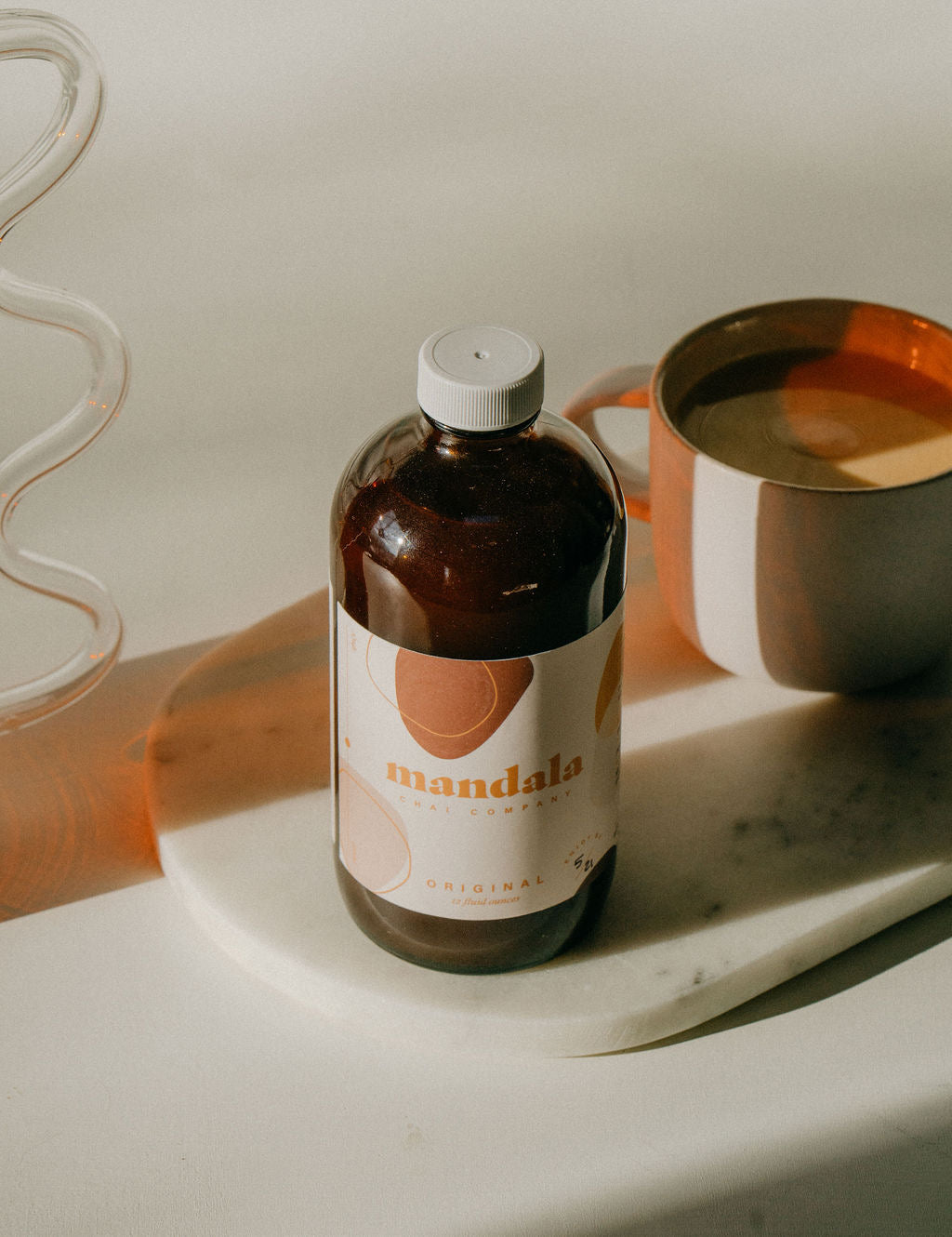 Original chai bottle on a marble board beside a chai latte