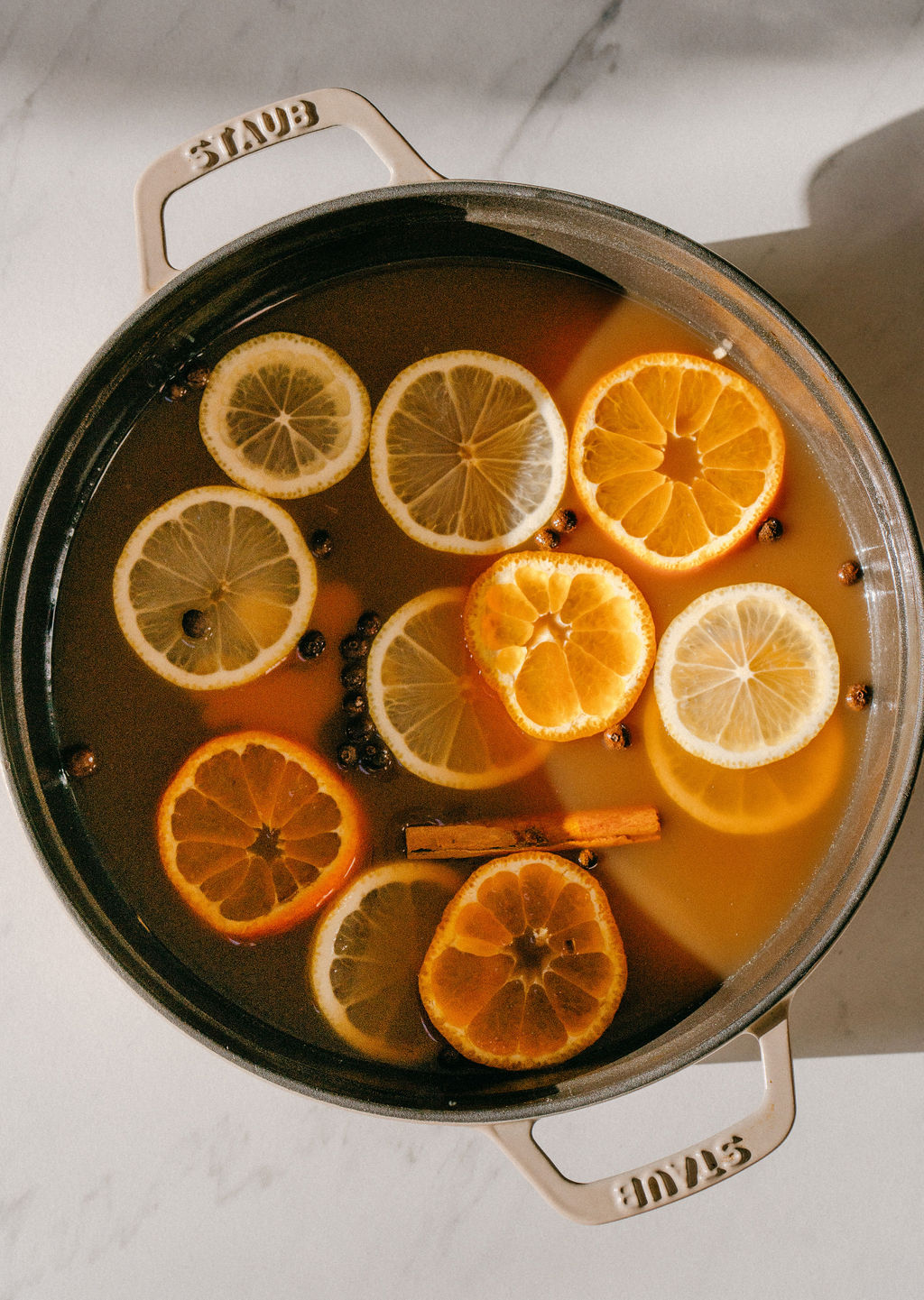 A pot of chai spiced apple cider with orange and lemon slices
